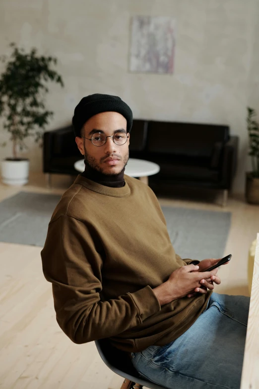 man wearing glasses is sitting on the bench with a cell phone in his hand