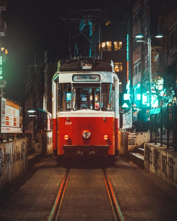 a red and white bus traveling on a street at night