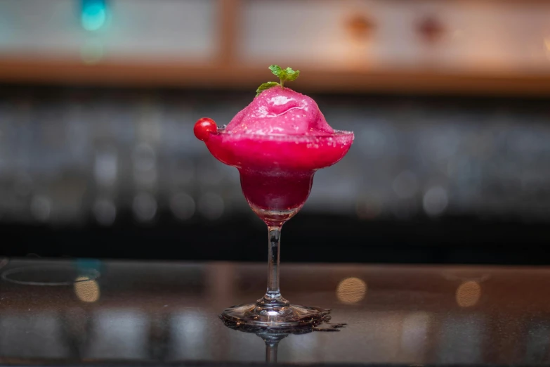 a cocktail sitting on a table that has a pink liquid in it