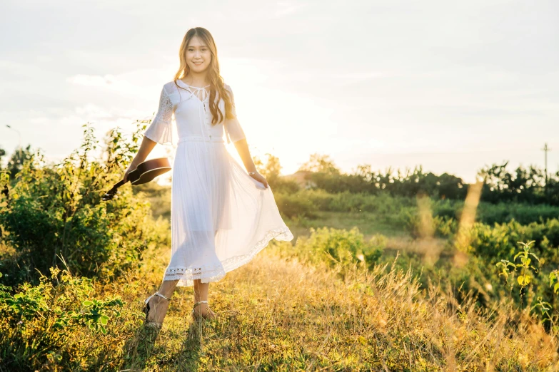 the young woman in the white dress is holding her hat