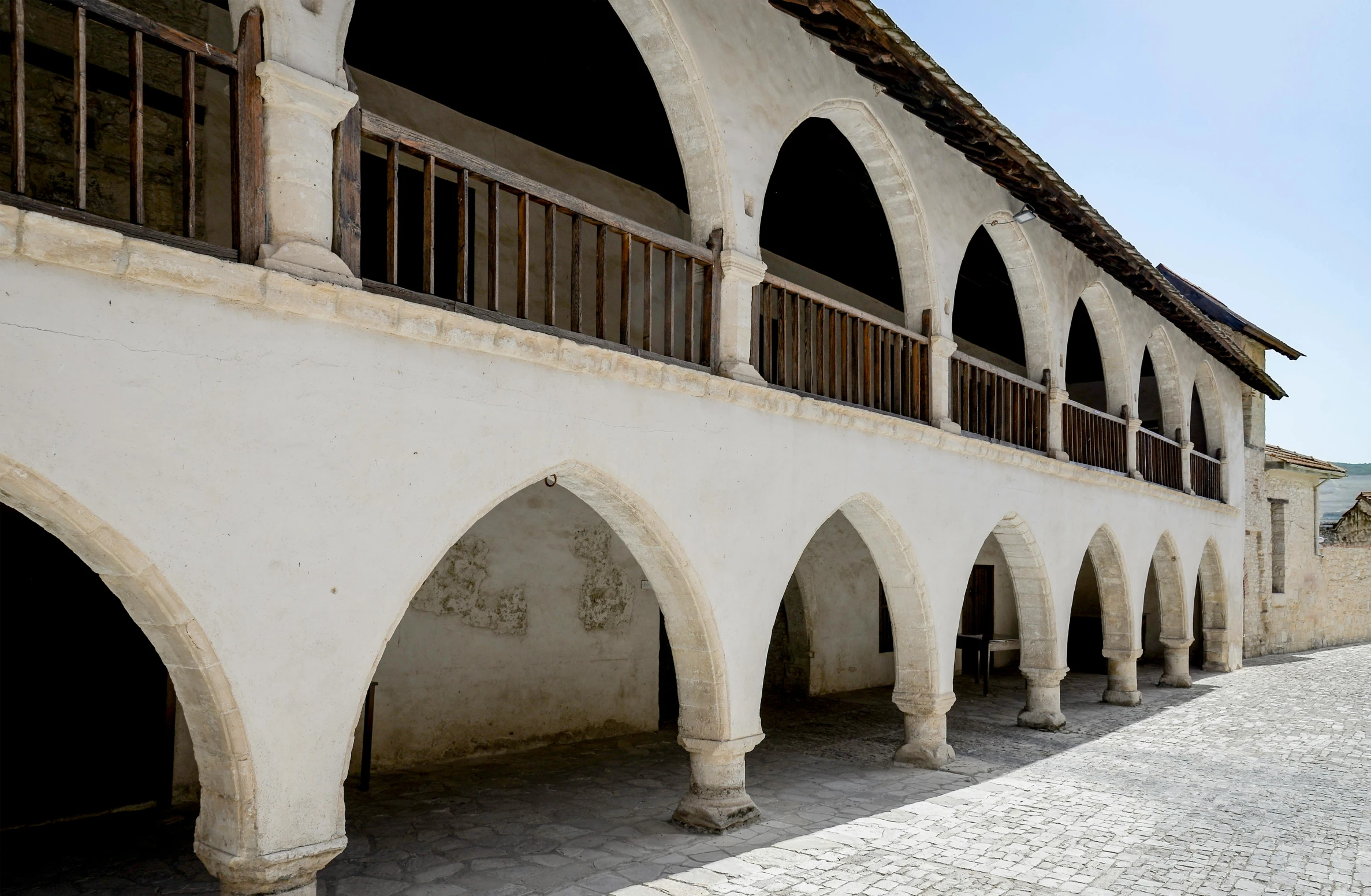 an outside area in a museum with a row of arches on the wall and multiple columns