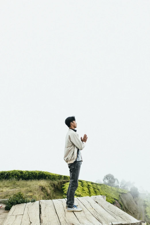 man with white jacket standing on wooden walkway and looking ahead