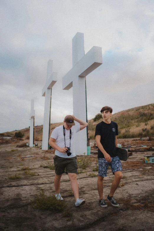 two young men standing next to each other in front of crosses