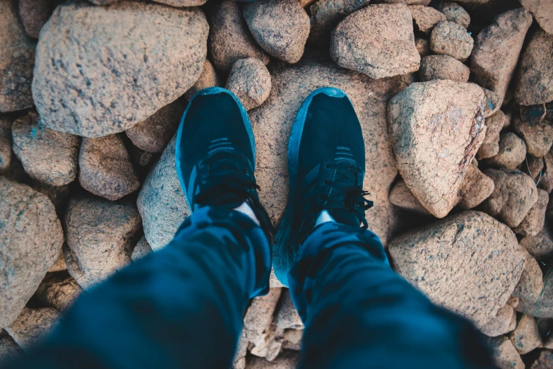 a pair of sneakers sitting on top of a pile of rocks