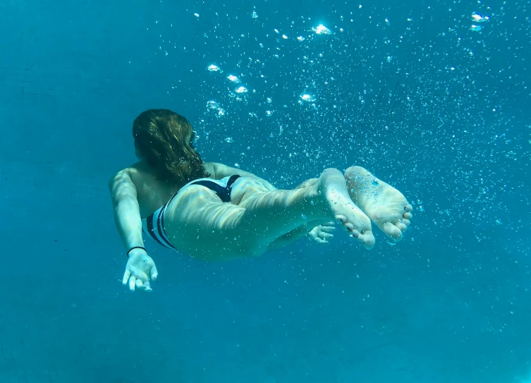 a woman floating under the water in a swim suit