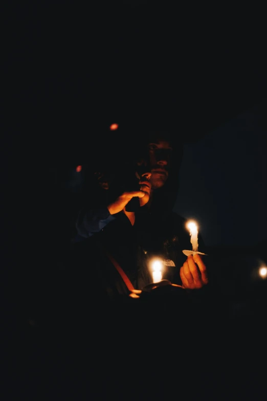 two men sitting at a table in the dark holding lit candles