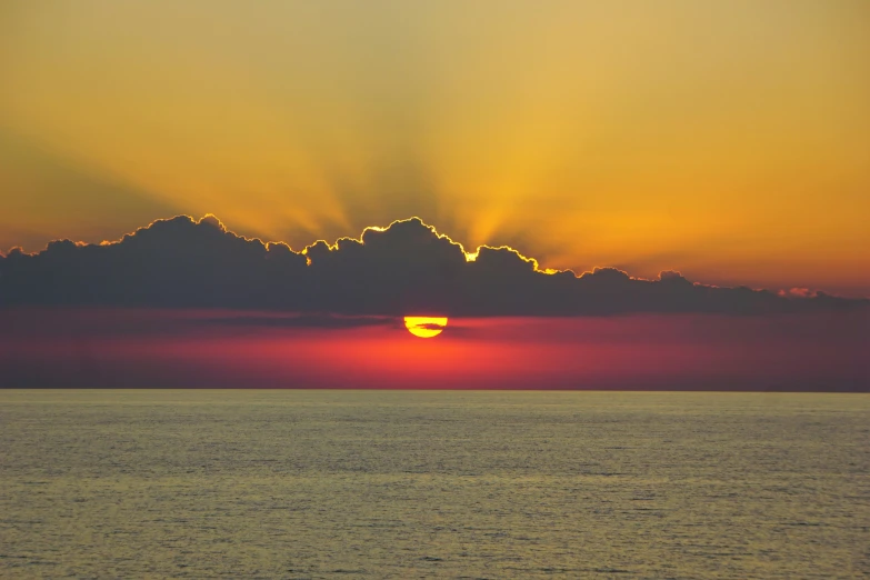 the sun shining behind a cloud on top of a hill