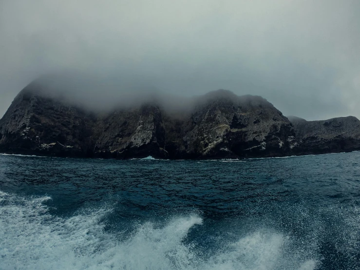 two mountains rise out from the ocean with a cloudy sky