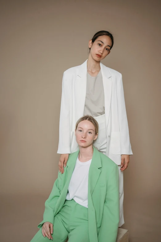 a woman wearing a white blazer and green pants