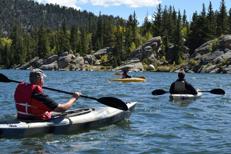 several people on kayaks in the water near rocks