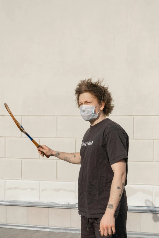 a man wearing a face mask holds a tennis racquet