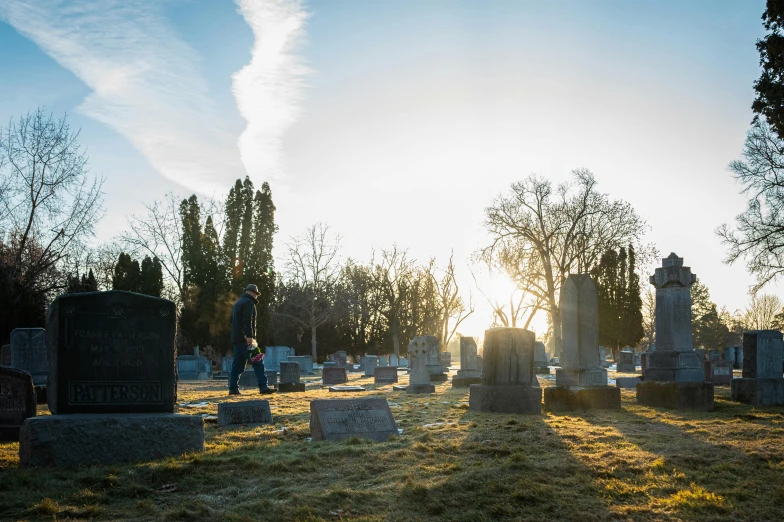 the sun sets in the background of the old cemetery with the sun shining through the trees