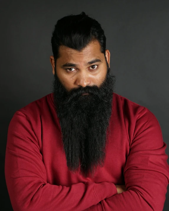 a man with long beard standing up with his arms crossed