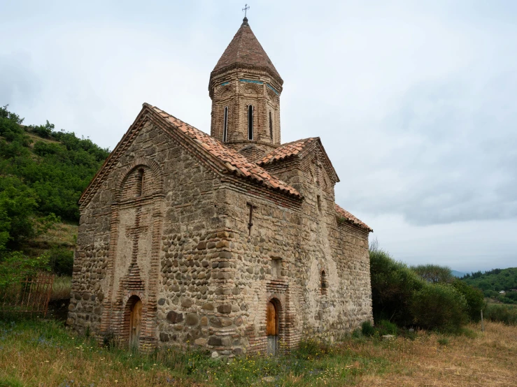 an old church in a small hill near trees