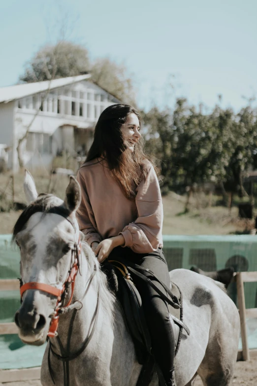 a young lady riding on the back of a grey horse