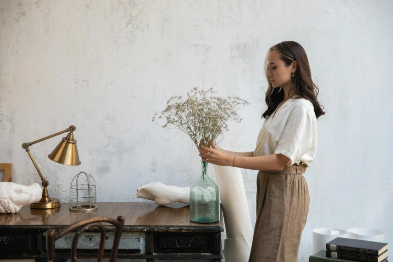 the woman is looking at the flowers in the glass bottle