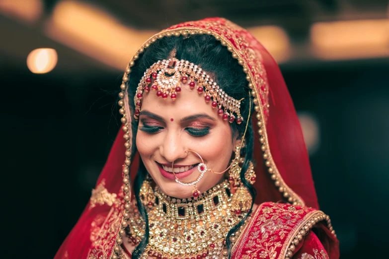 a woman in a red and gold wedding gown wearing a jewelry set and gold necklace