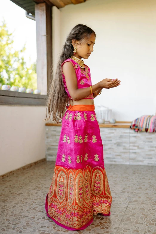 an indian girl wearing a colorful gown is looking at her cellphone