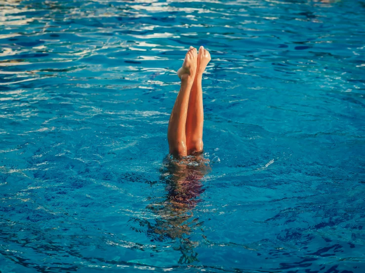 a person lying upside down in a blue swimming pool