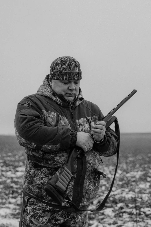 man is holding his rifle and standing on a rock