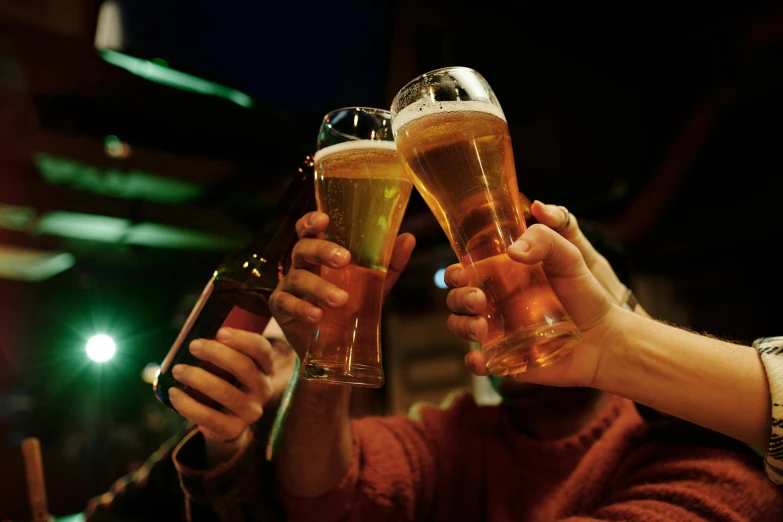 three people are toasting with two bottles in their hands