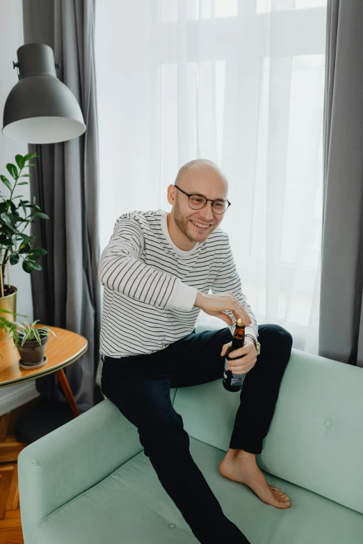 a balding man with glasses sitting on a couch