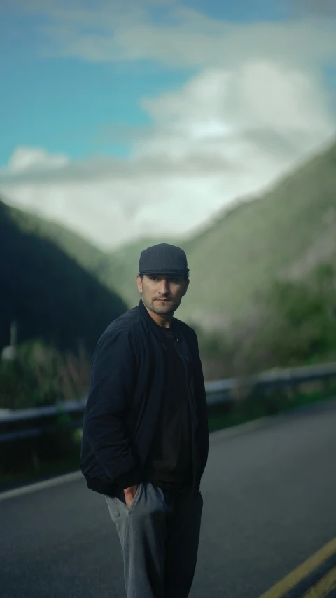 a man walking across a road with mountains behind him