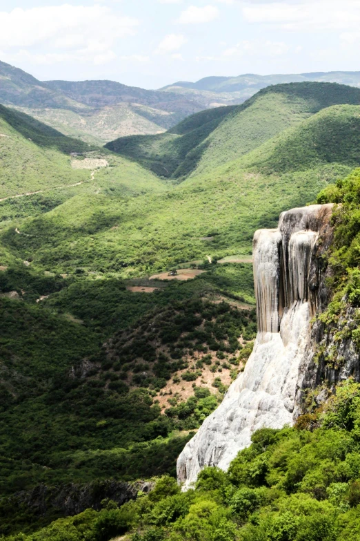 a cliff out over a valley, with very green mountains behind it