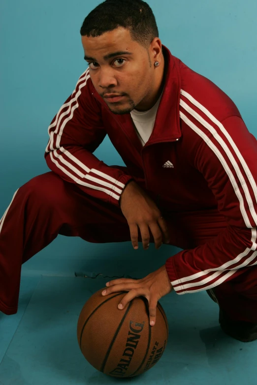 a man posing with his arms crossed and holding a basketball
