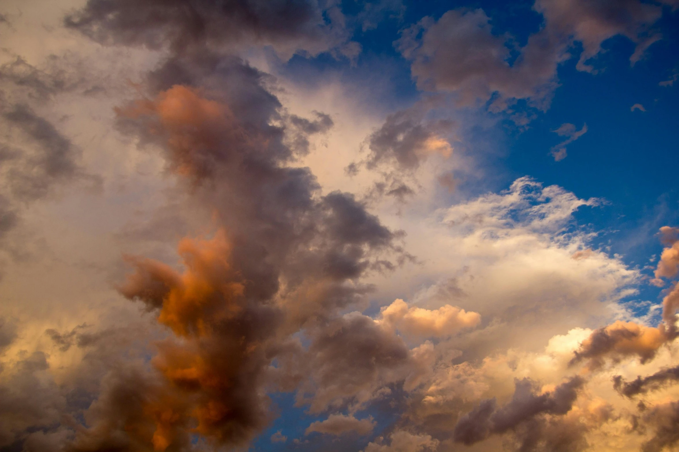 a sky filled with lots of clouds with the sun in the distance