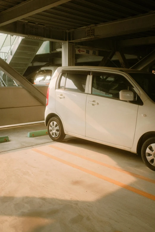 a small white car parked on the side of a train track