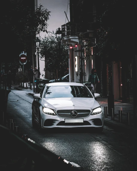 a white car is parked on a city street at night
