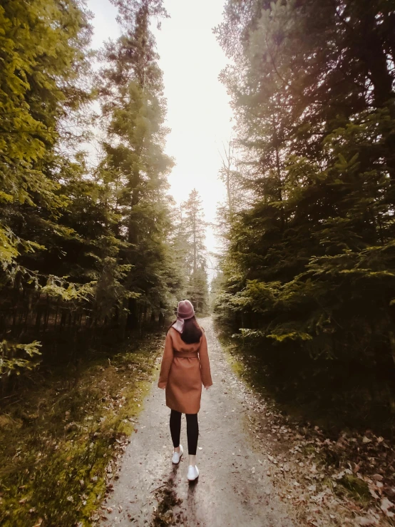 a woman in pink jacket walking down a path through a lush green forest