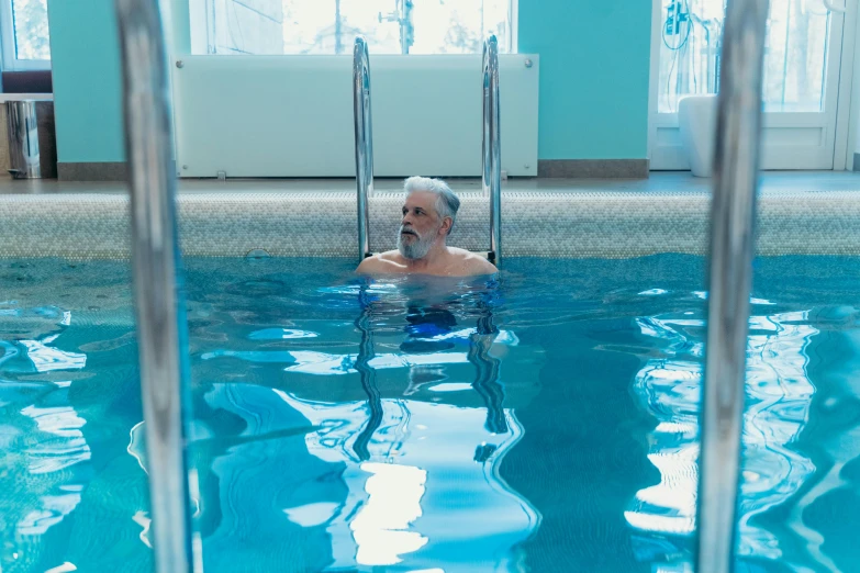 an old man sitting in the pool with clear water