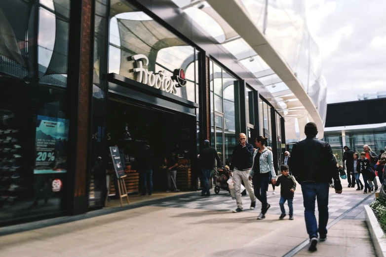 people walking on a sidewalk near a window of a shop