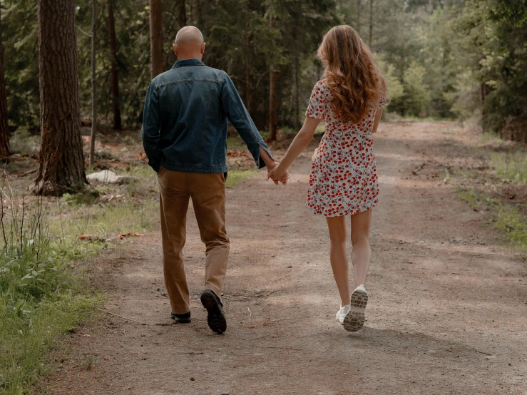 an older couple hold hands and walk down a trail