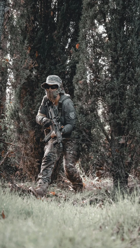 a man that is walking in the grass with a gun