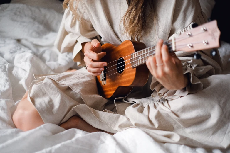 a woman sitting on a bed playing a guitar