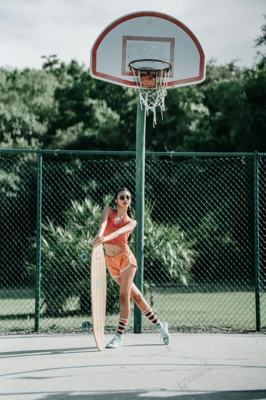 a woman in an orange outfit is playing basketball