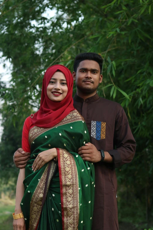 two people in dress clothes stand next to each other near trees