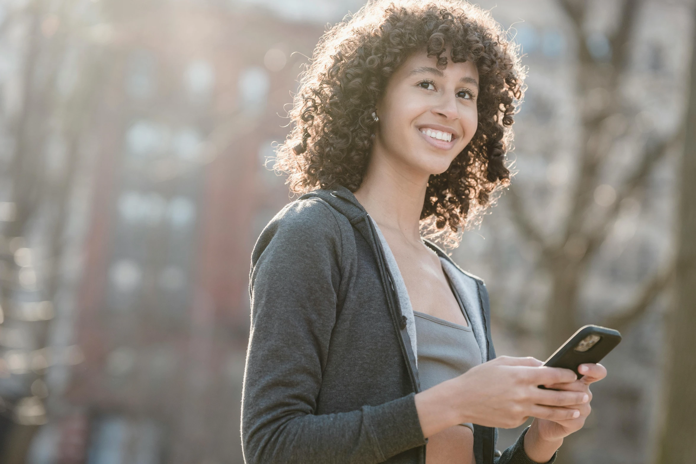 woman looking at her phone while standing in a city