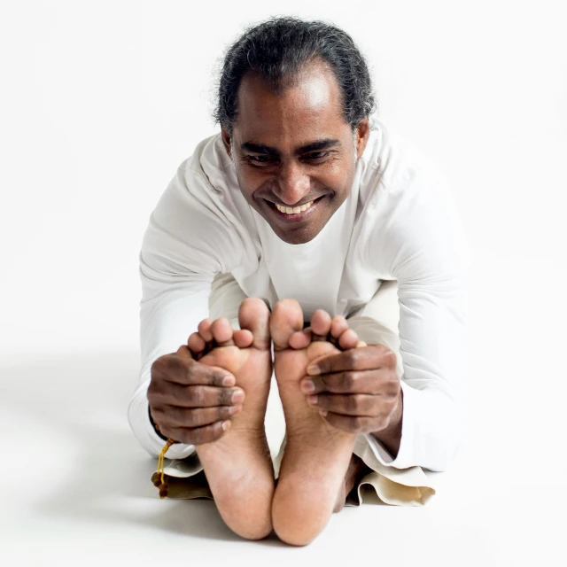 an indian man holding his toes up in front of the camera