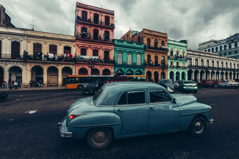 an old car driving in front of some old buildings