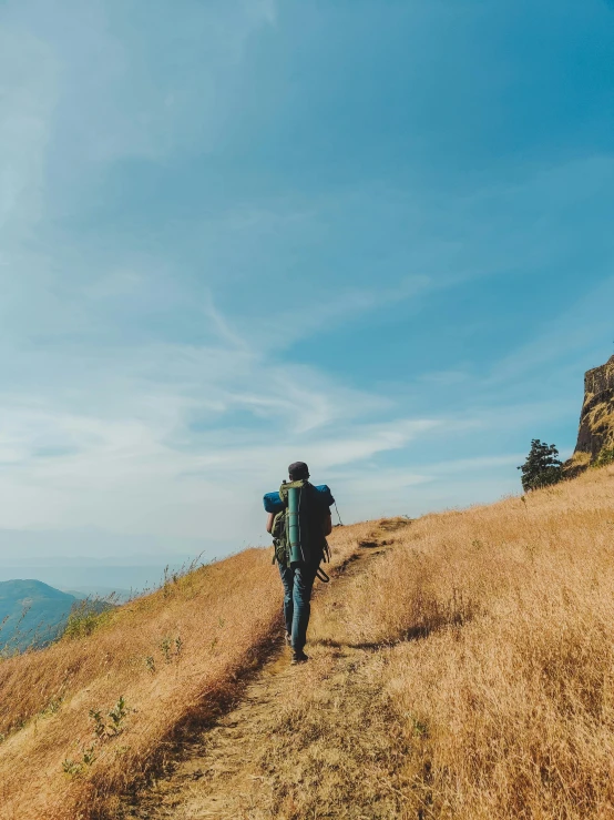 a lone hiker is walking across the grass on a mountain