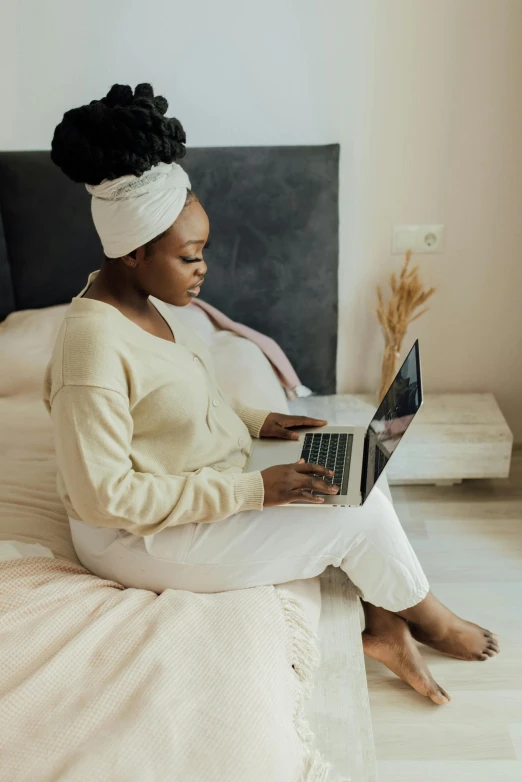 a woman is sitting on a bed with a laptop