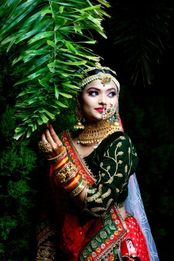 a girl in traditional clothing is standing with her hands on her head and the plants in her hand