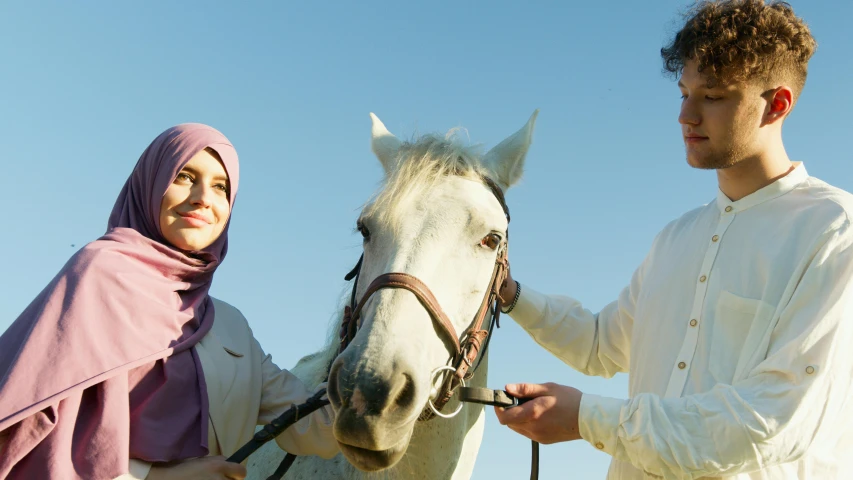two people in traditional arabic garb are holding a horse