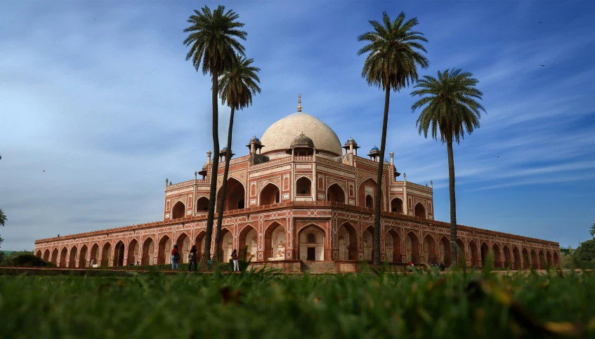 a beautiful building with two domes sits among palm trees