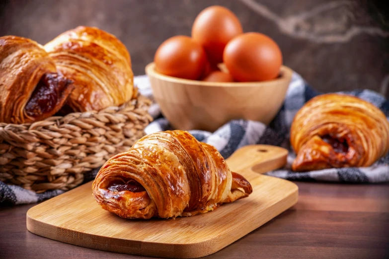 a wooden board topped with meat covered croissants