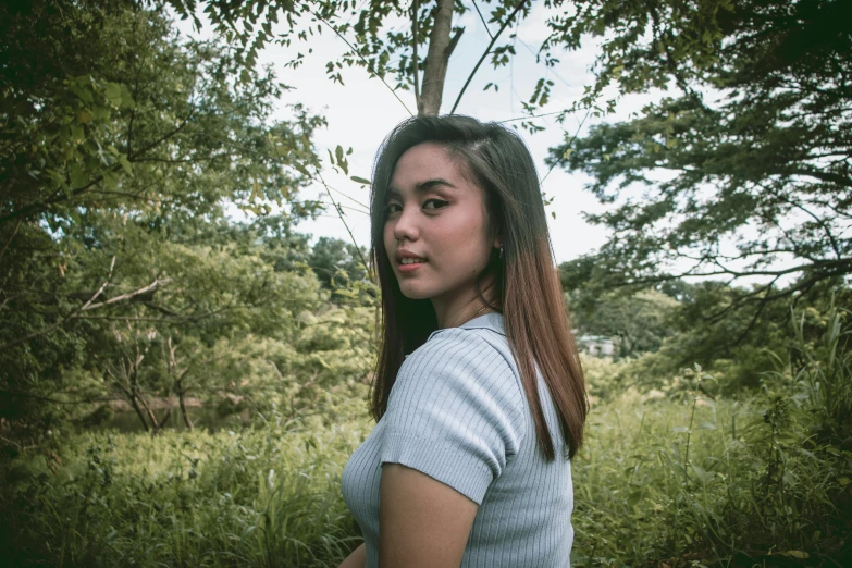 a woman poses for a portrait under some trees